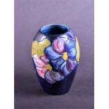 An early 20th century Moorcroft vase in the Clematis pattern  with tube-lined flowers on a blue