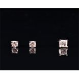 A pair of white metal and diamond ear studs each set with a round brilliant-cut diamond, the two