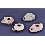 A collection of four ancient terracotta lamps, believed to be Roman one embossed with a stallion,