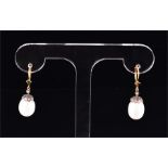 A pair of yellow metal and pearl drop earrings each with a white pearl, suspended from a silver