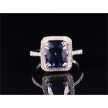 A 14ct white gold, diamond, and sapphire cluster ring set with a rectangular mixed-cut sapphire,