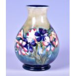 A William Moorcroft Spring Flowers pattern baluster vase with tube-lined decoration on a pale