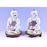A pair of 20th century Chinese export porcelain seated figures of boys holding peaces, with Canton
