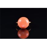 A yellow metal and coral ring set with a round coral, diameter 19mm, size Q 1/2, 6.2 grams.