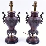A pair of Chinese bronze desk lamps formed from baluster vases flanked with beast handles, with