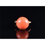A yellow metal and coral ring set with a large round coral, 13 mm, 5.5 grams.