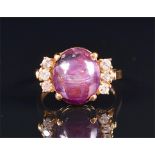 A diamond and star ruby ring set with an oval cabochon ruby, flanked with six round brilliant-cut