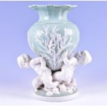 A large Minton porcelain sea sprite vase centrepiece formed as three mercherubs holding aloft a vase