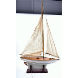 An early 20th century wooden pond yacht with cloth sails, on a wooden stand, 71 cm long x 125 cm (