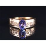 A 9ct yellow gold, diamond, and tanzanite ring set with an oval-cut tanzanite, the shoulders inset