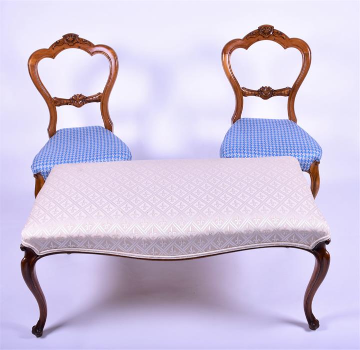 A French walnut upholstered double footstool with overstuffed top and supported on carved cabriole