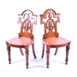 A pair of Victorian oak hall chairs backs with oval open work carving, solid seats, and supported on