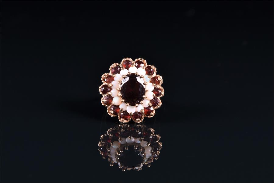 A 9ct yellow gold, garnet, and opal cluster ring the circular cluster centred with an oval-cut