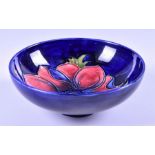 A small Moorcroft Anemone tubelined bowl decorated with a red flower on a deep blue ground,