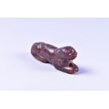 A small Chinese carved brown jade pendent modelled as a recumbent beast, 4.9 cm long.