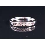 A 9ct white gold and diamond ring channel-set with a line of seven round brilliant-cut diamonds,