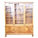 A large early 20th century pale oak triple bookcase with three glazed doors enclosing shelves,