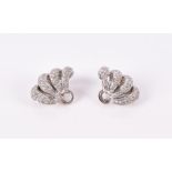 A pair of diamond earrings of swirled loop design, pave set with round brilliant cut diamonds, set