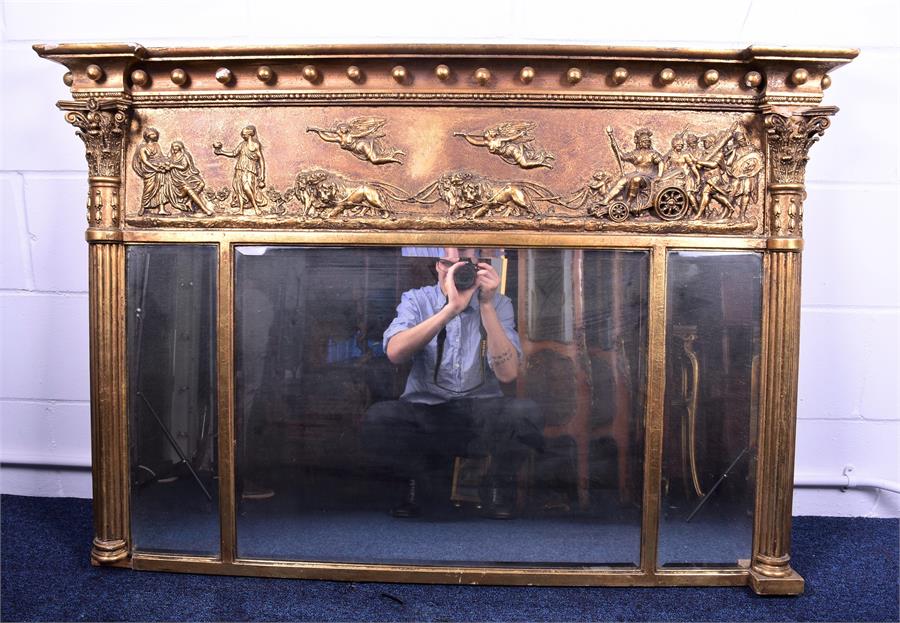 A large gilt overmantle triptych mirror   with Corinthian style columns flanking a relief decoration