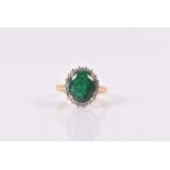 An emerald and diamond cluster ring set with an oval mixed-cut emerald, approximately 11 x 9 mm,