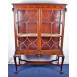 A large Edwardian Sheraton design mahogany glazed cabinet with carved floral pediment over a pair of