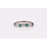 An 18ct white gold, diamond, and emerald ring set with three round-cut diamonds of approximately 0.