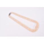 A triple strand pearl necklace of evenly-coloured graduated pearls, fastened with an 18ct white