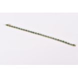 An 18ct yellow gold, diamond, and emerald line bracelet set with oval-cut emeralds of