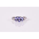 A 14ct white gold and tanzanite ring set with three oval-cut tanzanites, with diamond accents to