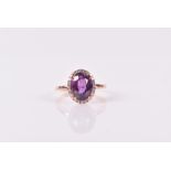 An 18ct rose gold, diamond, and purple sapphire cluster ring set with an oval-cut sapphire of