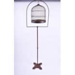 An early 20th century brass hanging bird cage supported on a cast iron stand, 168 cm high.