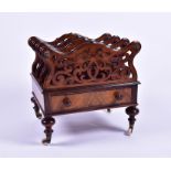 A Victorian burr walnut Canterbury with pierced scroll panels and a front drawer, raised on turned