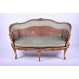 A large 19th century French bergere sofa in the Louis XV style, with gilded carved frame and drop-in