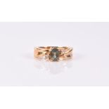 A yellow metal and Alexandrite crossover ring set with an oval-cut green Alexandrite with two