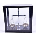 A set of large weighing scales in a wood and glass display case.