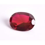 An unmounted oval mixed-cut synthetic ruby measuring 20 x 15.13 x 7.6 mm.