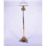 A Victorian brass standard lamp and shade converted to electricity, with a graduated stem, supported