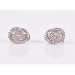 A pair of 18ct white gold and diamond earrings of swirled design inset with round and baguette-cut