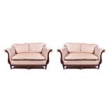 A pair of Regency style scroll-end sofas with curved scrolling arms, upholstered in cream and gold