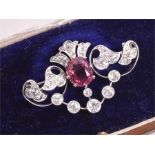 A diamond and pink tourmaline brooch set with an oval cushion-cut tourmaline, the openwork mount set