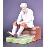 A Russian Gardner porcelain factory figurine modelled as a bisque porcelain old man sat on a group