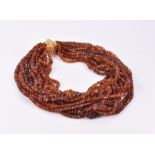 A multi-strand amber-coloured gemstone bead necklace comprising fourteen strands of faceted beads,