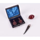 A pair of paste garnet drop earrings together with an egg-shaped amber pendant, and an unusual