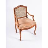 A Louis XV style French carved walnut armchair designed with carved floral motifs, the flat back and