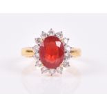 An 18ct yellow gold, diamond, and ruby cluster ring set with a mixed oval-cut ruby, of approximately