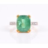 A yellow metal, diamond, and emerald ring set with a mixed rectangular-cut emerald, approximately 10