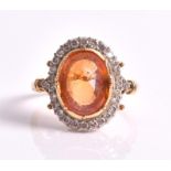 An orange sapphire and diamond cluster ring  centred with an oval mixed-cut orange sapphire weighing