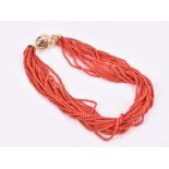 A multi-strand coral necklace the beads approximately 3 mm diameter, fastened with an 18ct yellow