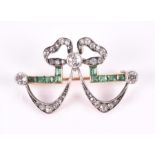 A diamond and emerald bow brooch of elegant form, centered with an old-cut diamond of