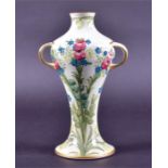 A Macintyre William Moorcroft tubelined twin handled vase decorated with flowers and leaves on a